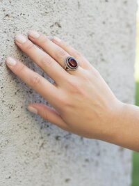 Faceted Garnet Ring with Rope Edge worn by model leaning against a stone wall