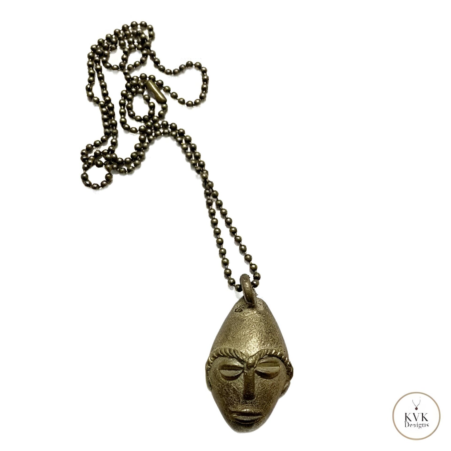 A brass necklace with a ball chain and a pendant shaped like a stylized, elongated face with distinct facial features, displayed on a white background.