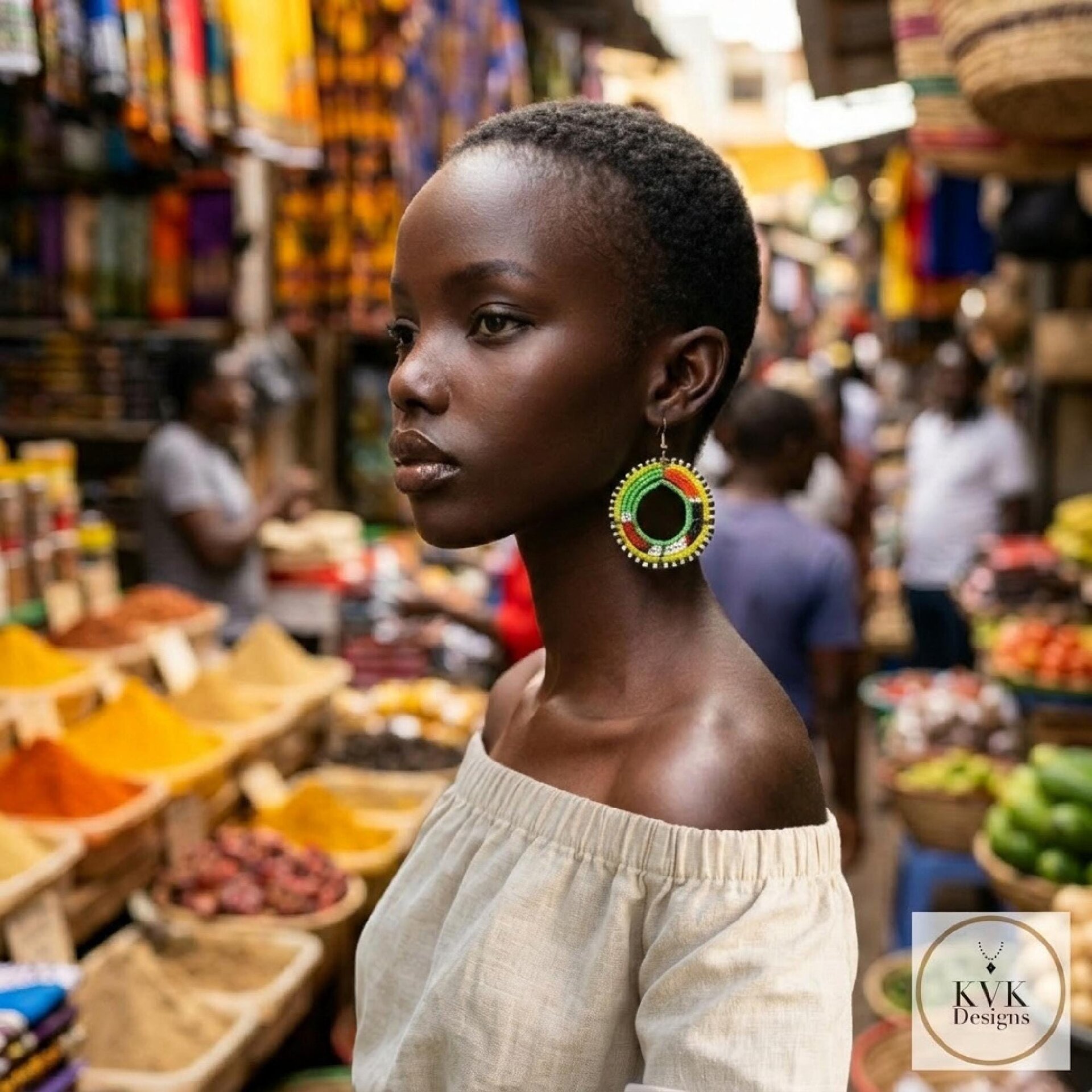 A woman with short hair and large, colorful beaded earrings stands in a vibrant outdoor market, surrounded by spices and fabrics. She wears an off-shoulder beige top.